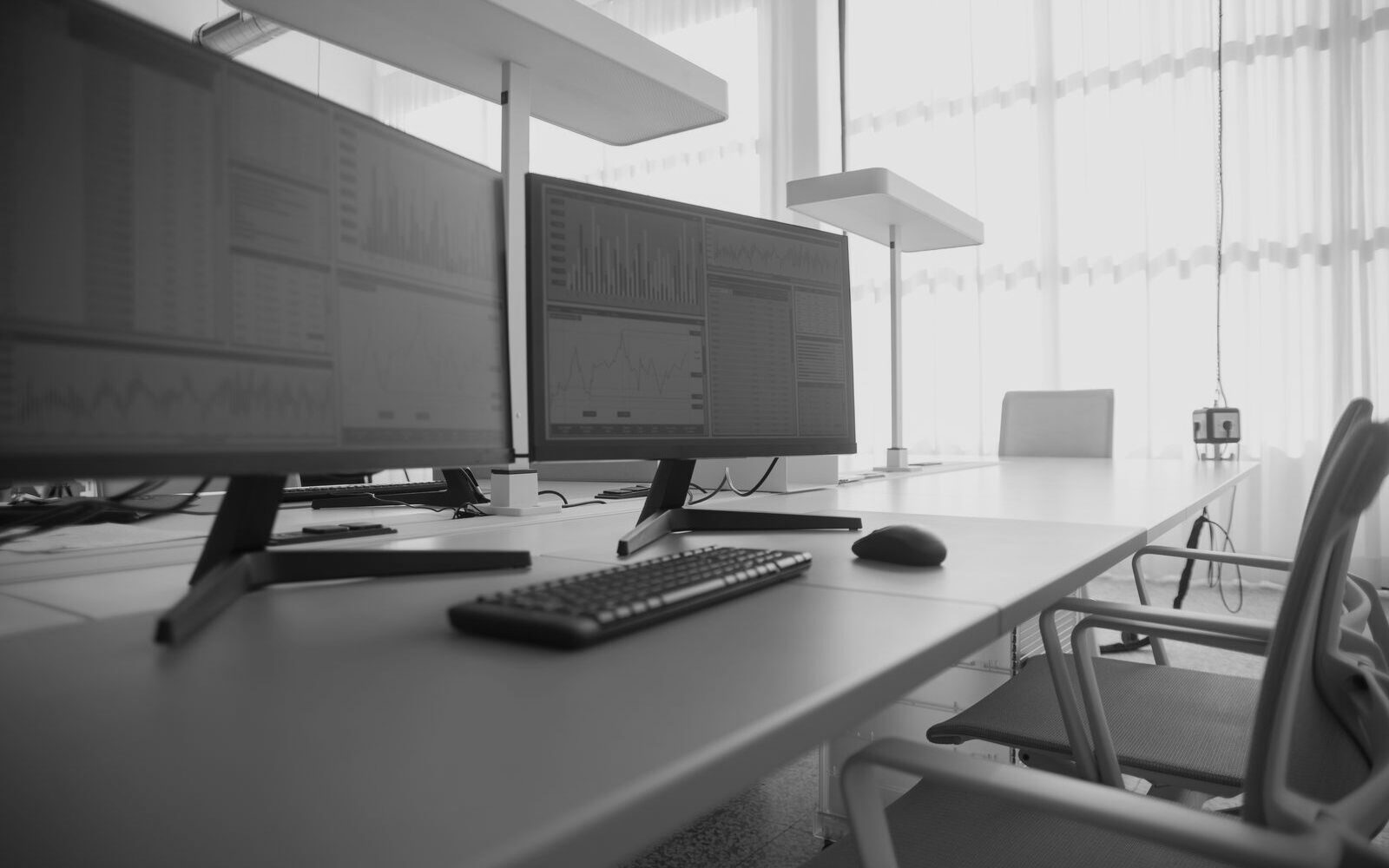 Two screens showing charts on a desk in a bright office